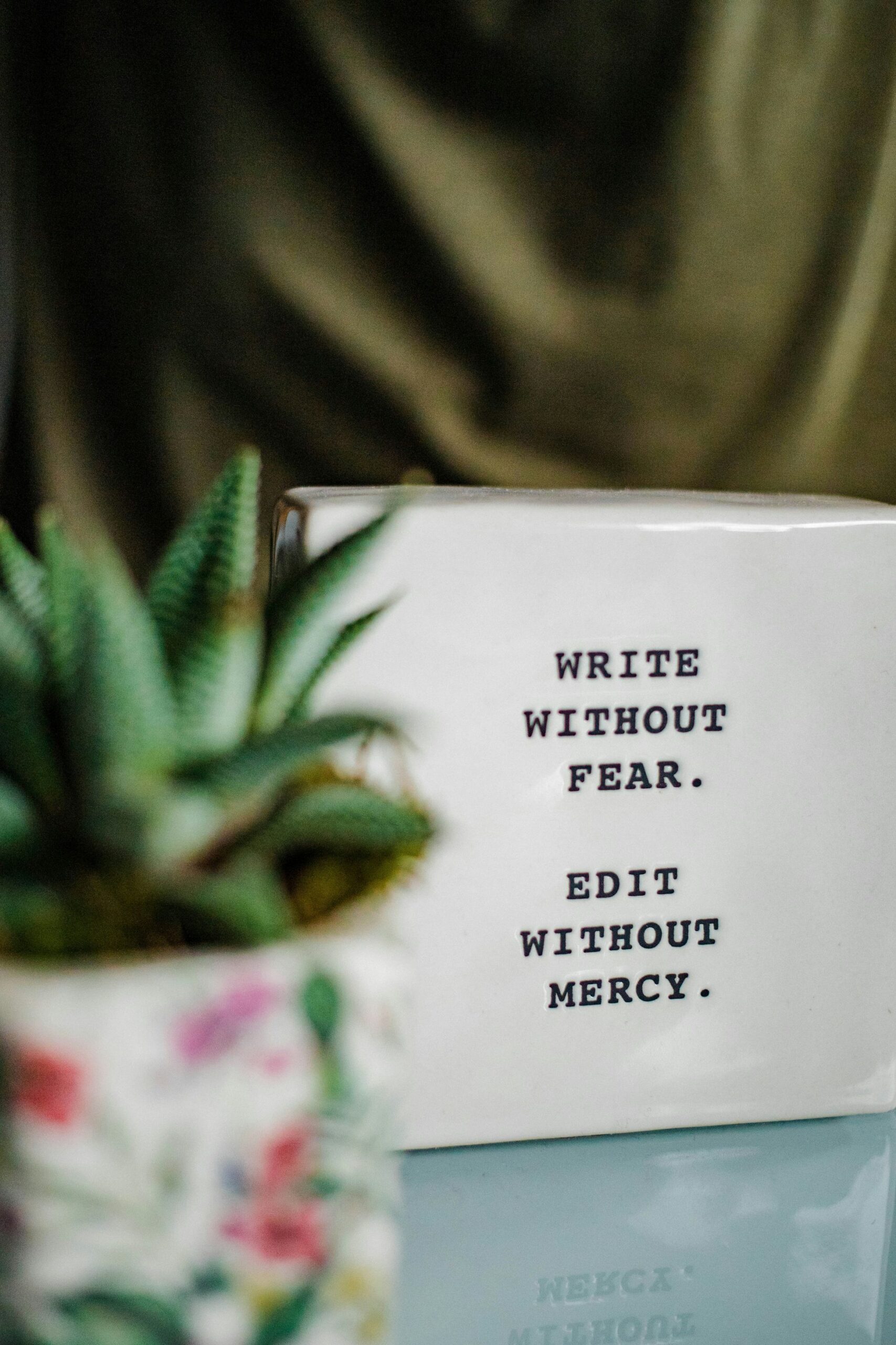 A sign, placed on a table top, reads 'Write without fear. Edit without mercy.' This UK freelance editor and proofreader endorses this statement!